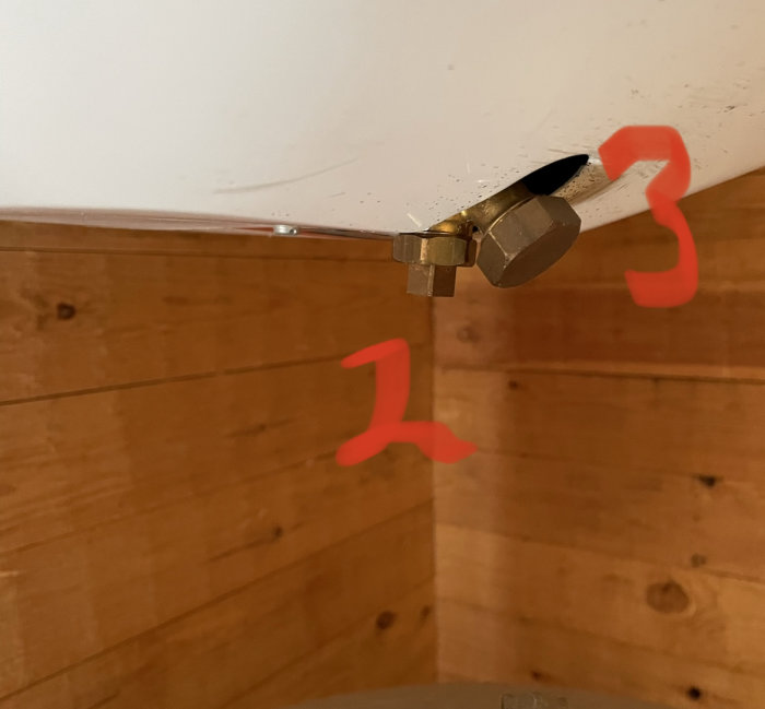 Anslutningar på en beredare märkta med röda siffror 1 och 3 mot en trävägg.