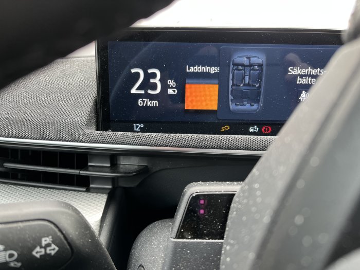 Bilens display visar 23% batterinivå med räckvidd på 67 km och en laddningsskärm vid 12 grader Celsius.