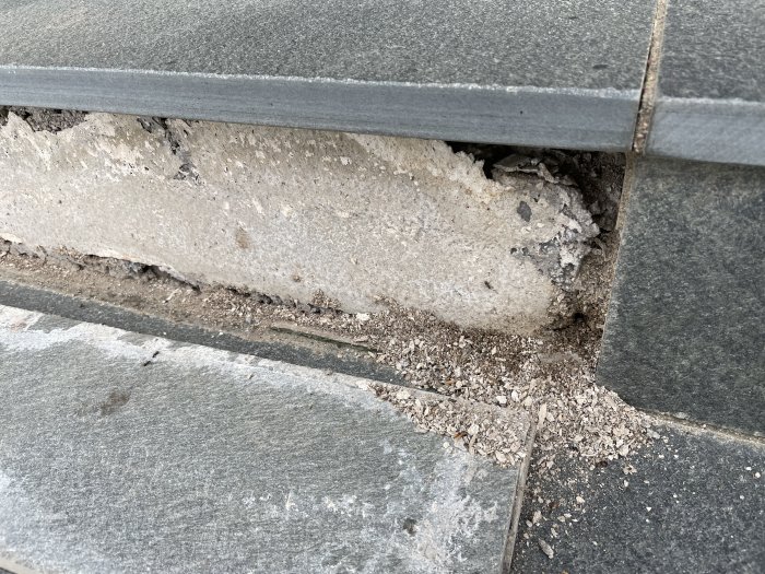 Skador på yttertrappa där stenplattor släppt och exponerat underlagen.