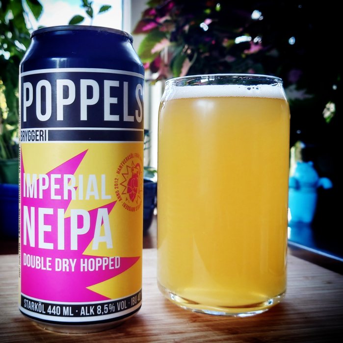 Poppels bryggeri Imperial Neipa ölburk bredvid fyllt glas med öl på bord.