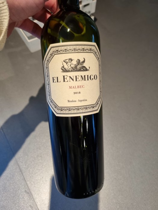 Flaska av El Enemigo Malbec 2018 från Mendoza, Argentina, hålls i handen.