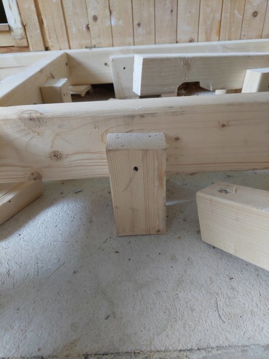 Träregelverk för golv med en kloss som stöd, där vissa reglar och stödklossar är lite sneda och en kloss är spräckt.