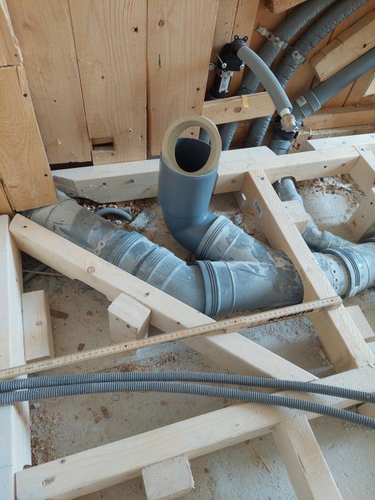 Konstruktion av träreglar i pågående badrumsrenovering med synliga vattenrör och avlopp.