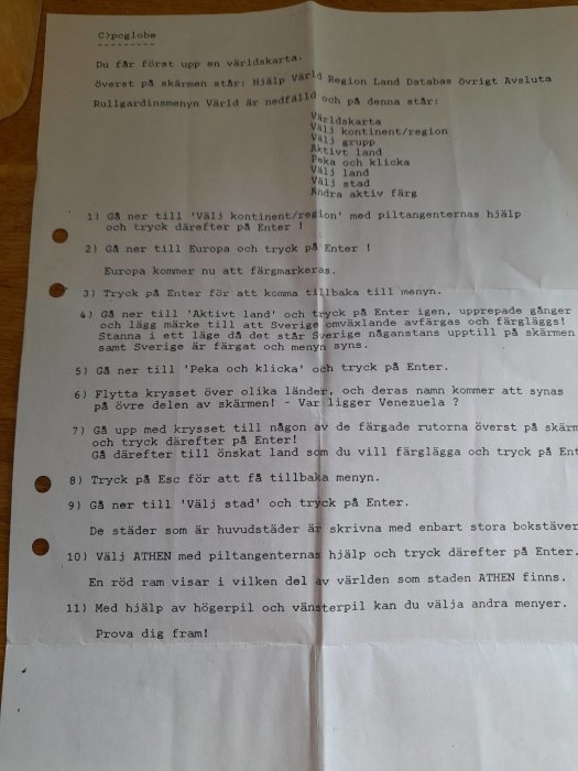 Ett gulnat pappersark med instruktioner för ett dataprogram vid namn "pcglobe" med steg-för-steg instruktioner från en datalektion på 1990-talet.