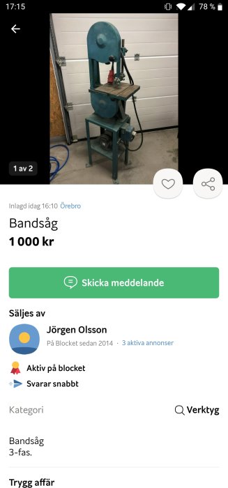 En blå bandsåg på ett metallställ med bord och hjul, placerad i en verkstad.