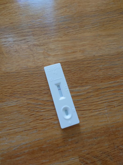 Negativt COVID-19 snabbtest ligger på ett träbord.