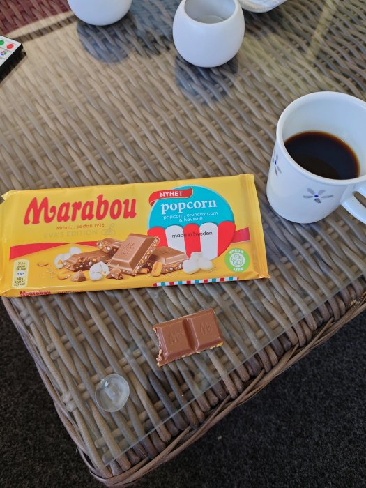 Marabou choklad med popcorn på vardagsrumsbord, kaffekopp och två vita vaser i bakgrunden.