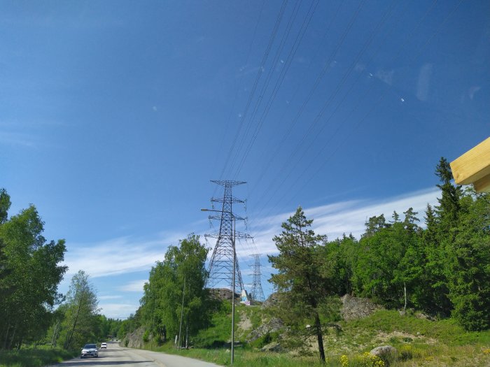 Kraftledning med ovanlig konfiguration av linor och stolpar söder om Stockholm under en klarblå himmel.