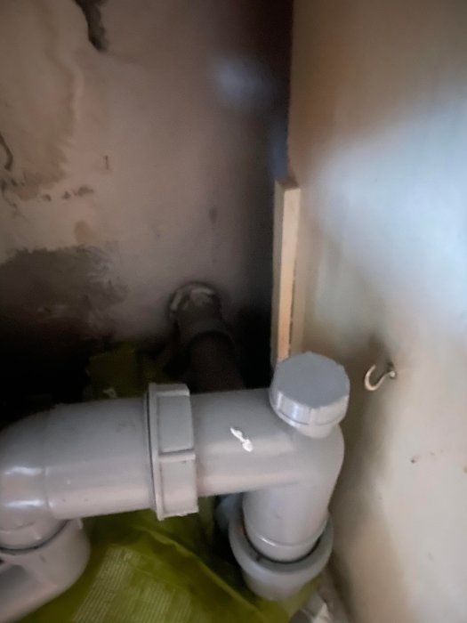 Avloppsrör och kopplingar i ett köksskåp, med fokus på en potentiell omplacering vid renovering.