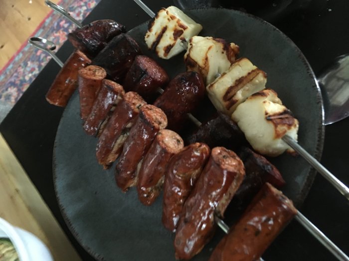Grillspett med grillost och olika korvar serverade på en tallrik.
