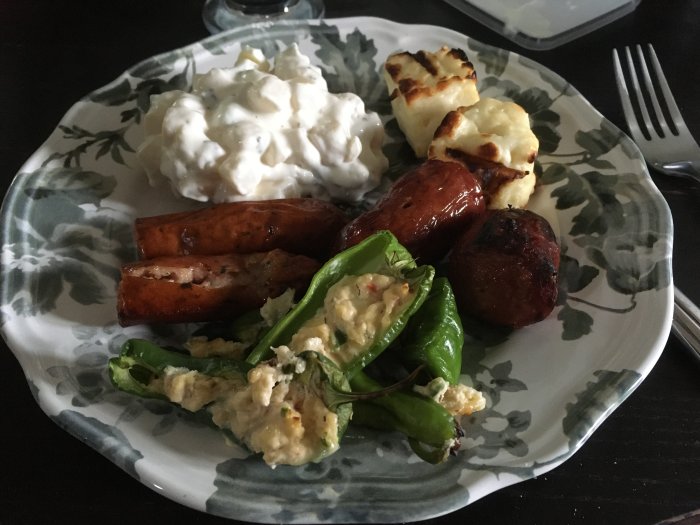 Grillspett med grillost, kycklingkorv och kabanoss, serverat med potatissallad på ett mönstrat fat.