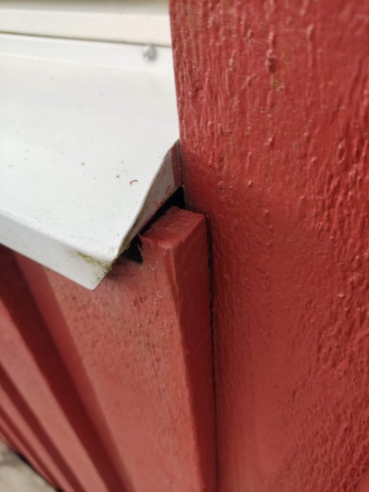 Ett stort hål mellan ett vitt fönsterbleck och en röd träfasad, där fyllning och tätning efterfrågas.