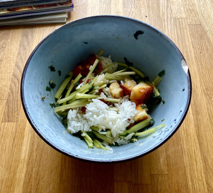 Asiatisk mangosallad med stekt halloumi i en blå skål på ett träbord.