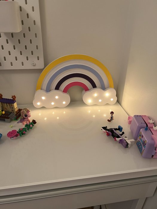 Handgjord regnbågslampa i flera färger med tända ljuspunkter på ett barnrumsskrivbord.