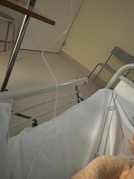 Patientens perspektiv inne på ett sjukhusrum med IV-stativ och sängkanter.