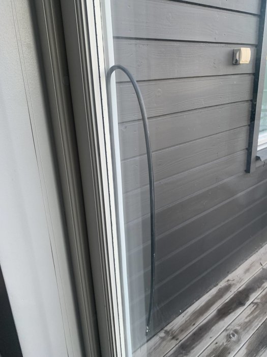 Fönster med lös list och synlig svart tätningslist mot grå trävägg.