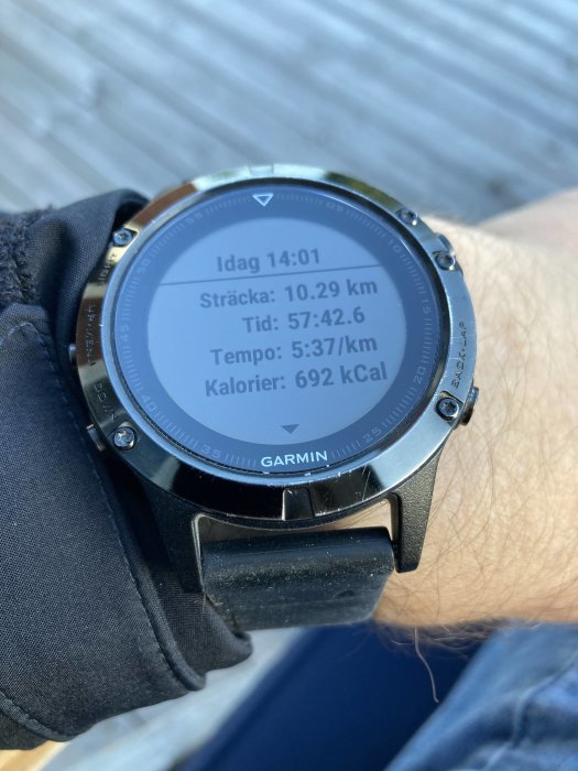 En person bär en Garmin sportklocka som visar data från en löprunda: sträcka, tid, tempo och förbrända kalorier.