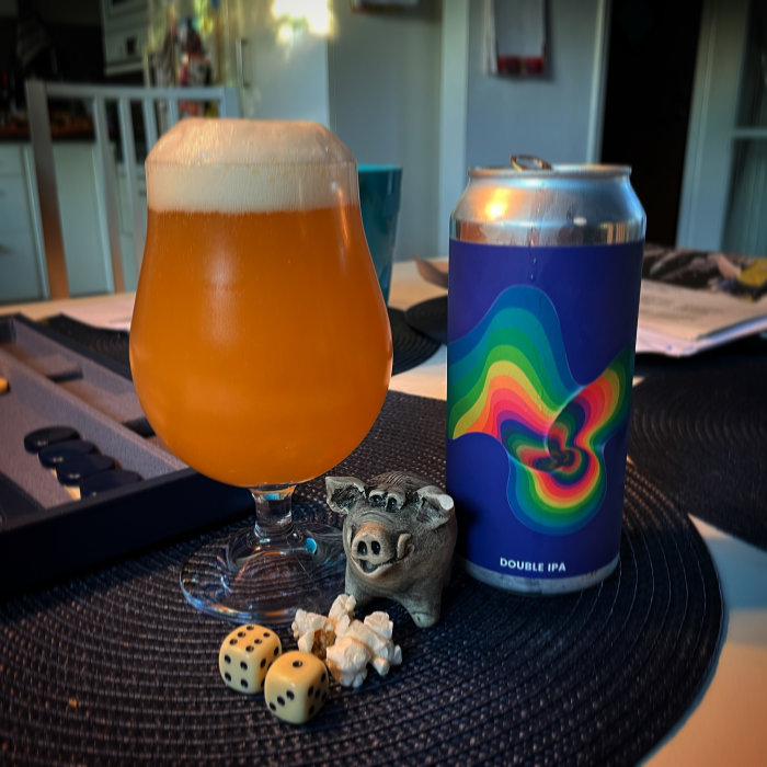 En ölglas fylld med hazy IPA bredvid en burk Double IPA, tärningar och en liten skulptur av en koala.