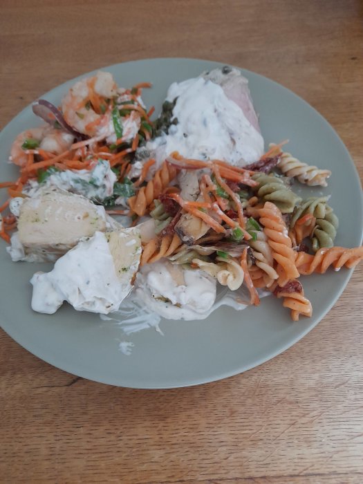 Restmat på tallrik inklusive pastasallad, kalvkött, morotsallad med scampi och kycklingfilé.