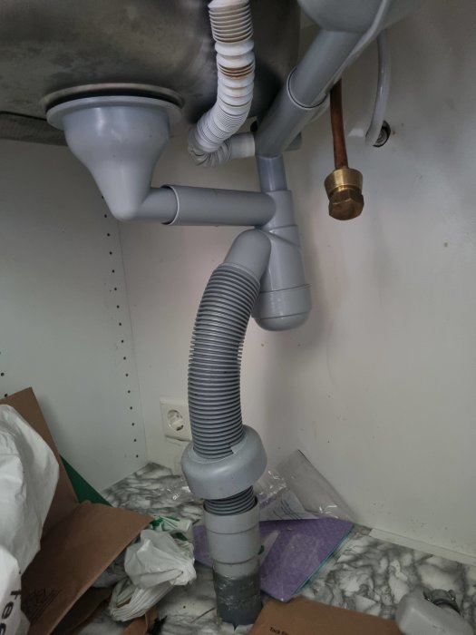 Röranslutning under diskho med flexibel avloppsslang och olika kopplingar, problematisk installation.