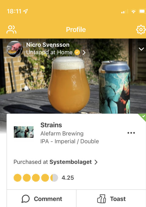Ölglas fyllt med grumlig öl och en burk från Alefarm Brewing på ett träbord.