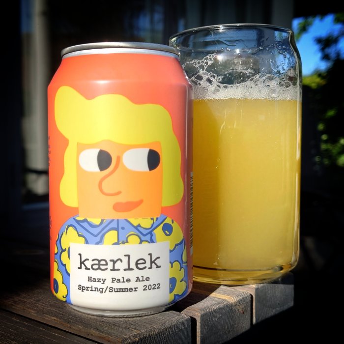 Ölburk med texten "kärlek" och ett glas med hazy pale ale, ute i solen.