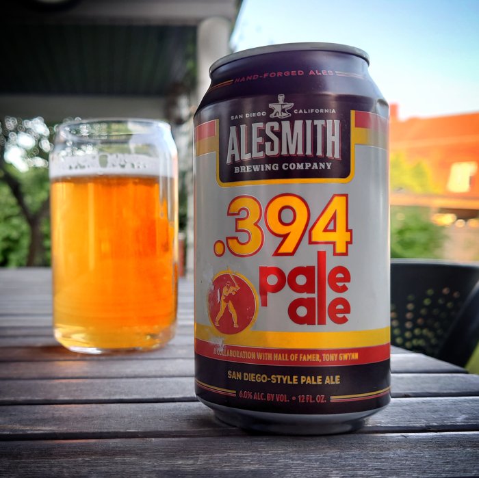 En ölburk av märket Alesmith .394 pale ale på ett träbord med ett glas öl i bakgrunden.