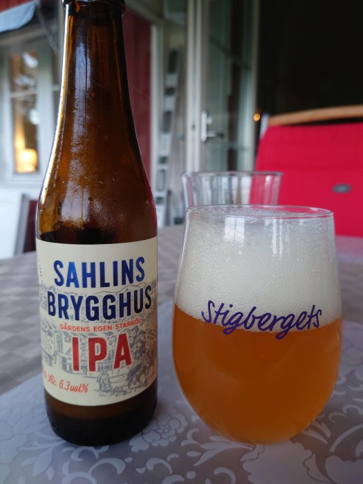Flaska och glas med öl från Sahlin Brygghus på ett bord, skummande IPA i fokus.
