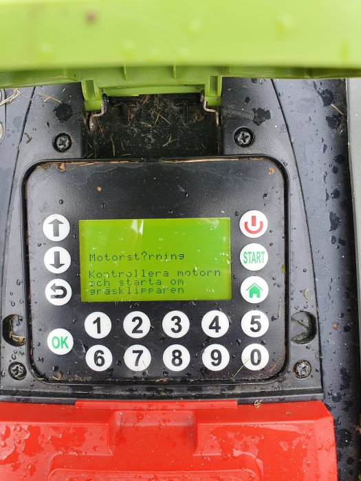 Kontrollpanel på en gräsklippare med felmeddelande på skärmen och knappsats.