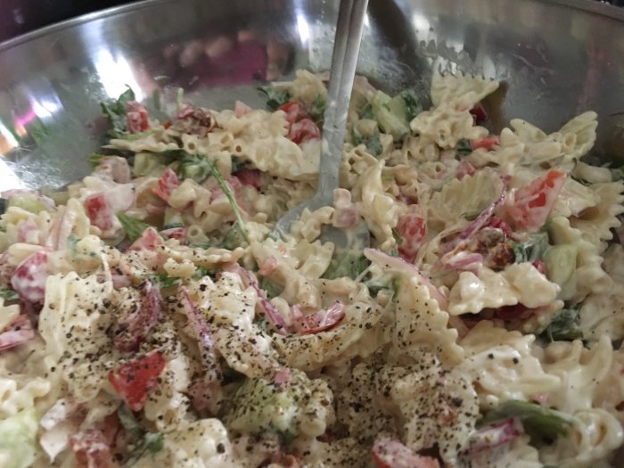 Pastasallad med gurka, ruccola, rädisor, paprika, soltorkad tomat och rödlök, toppad med svartpeppar.
