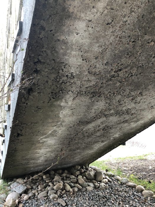 Porös betongtrappa med grus och småstenar vid basen som visar tecken på erosion.