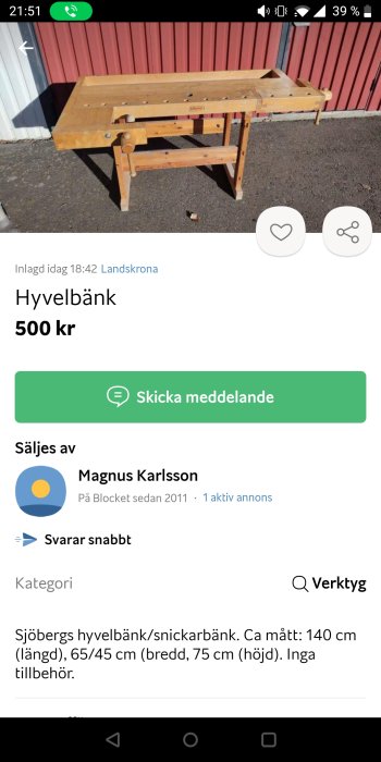 Använd hyvelbänk av trä framför röd byggnad, synlig i dagsljus.