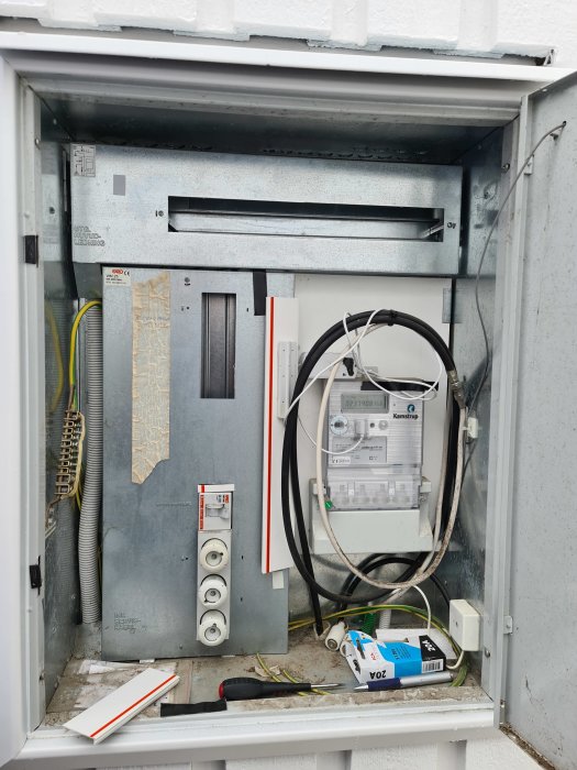 Öppet fasadmatarskåp med installerad smart mätare, växelriktare och kablage.