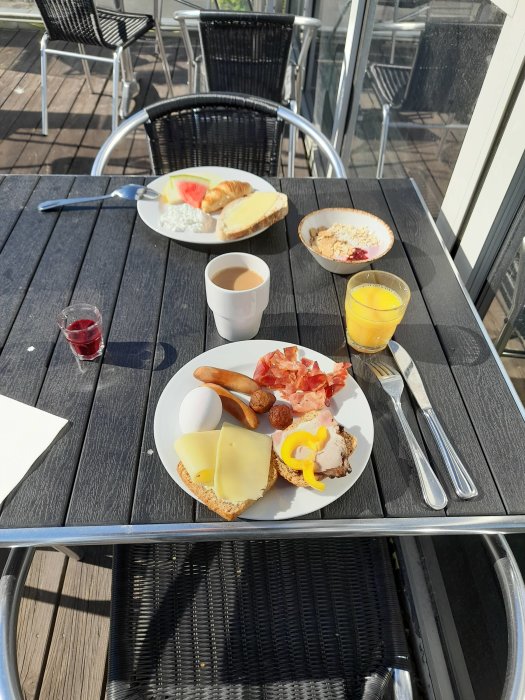 Frukosttallrik utomhus med skinka, ägg och juice på hotell i Stockholm med solsken.