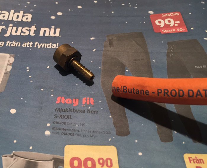 Gaskabel och nippel för husvagn ligger på en reklambroschyr.