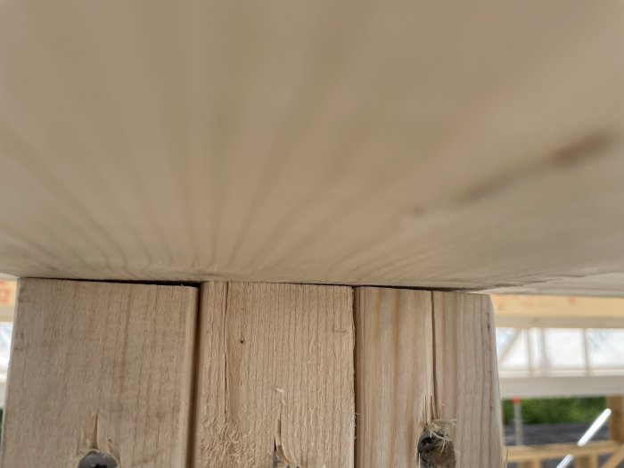 Limträbalk som vilar på ojämnt kapade, spiklimmade reglar med synlig bristande anläggningsyta.