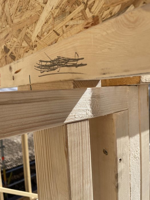 OSB-skiva och träreglar i en delvis byggd konstruktion med synliga spikar.