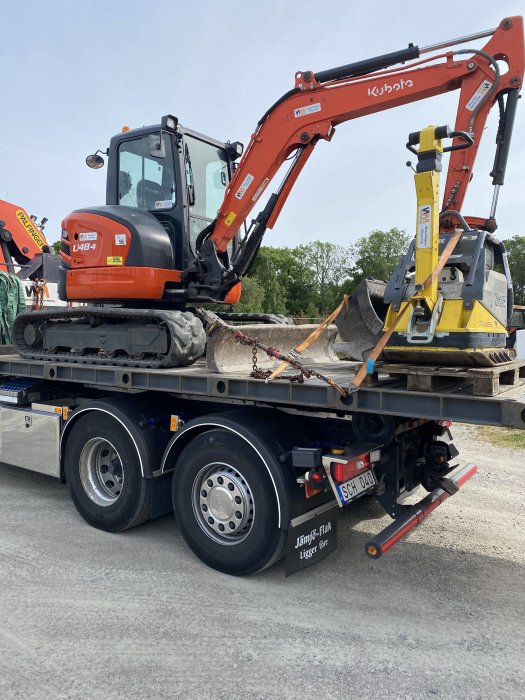 Kubota grävmaskin L4484 på en lastbilstrailer redo att användas för schaktarbete till en uteplats.