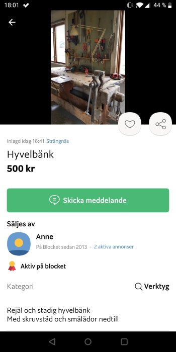 Arbetsbänk i en verkstad med skruvstäd, diverse verktyg på väggen och lådor under bänken.