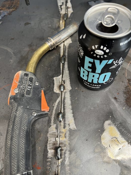 Svetsutrustning och en burk öl på en sliten arbetsbänk.