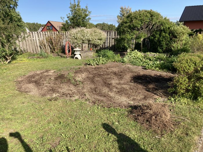 Nyjordade ytor i trädgård förberedda för att så gräs och anlägga sandlåda samt pallkragar.