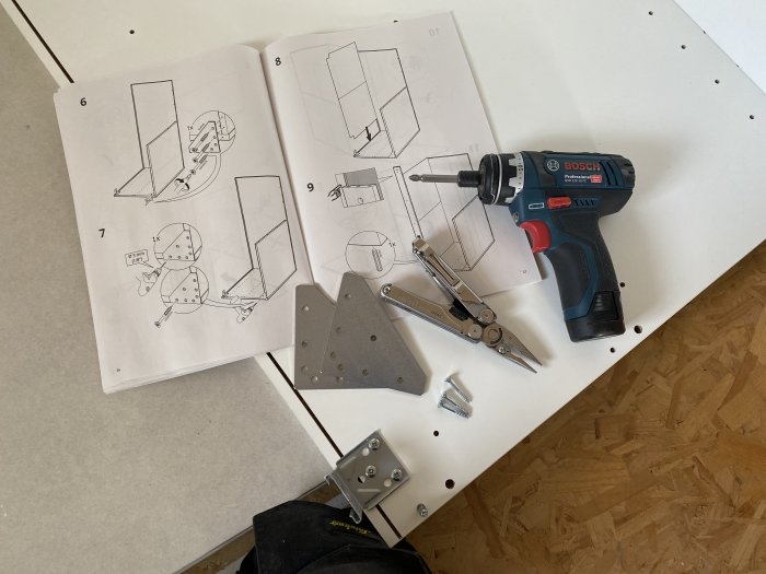 Instruktionsmanual för möbelmontering med skruvmejsel, skruvar och verktyg på ett bord.
