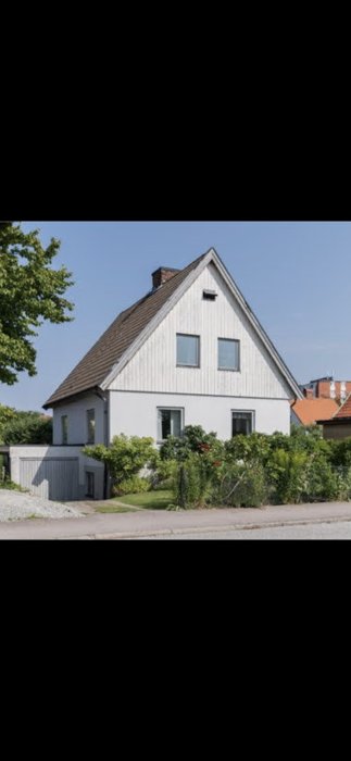 Tvåvåningshus med vit fasad och svart tak i behov av renovering till 20-talsstil.