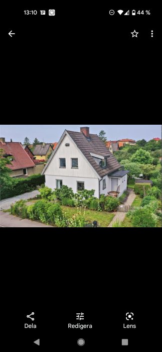 Hus från 1920-talet med vit fasad och svart tak i behov av renovering för att återskapa historisk stil.