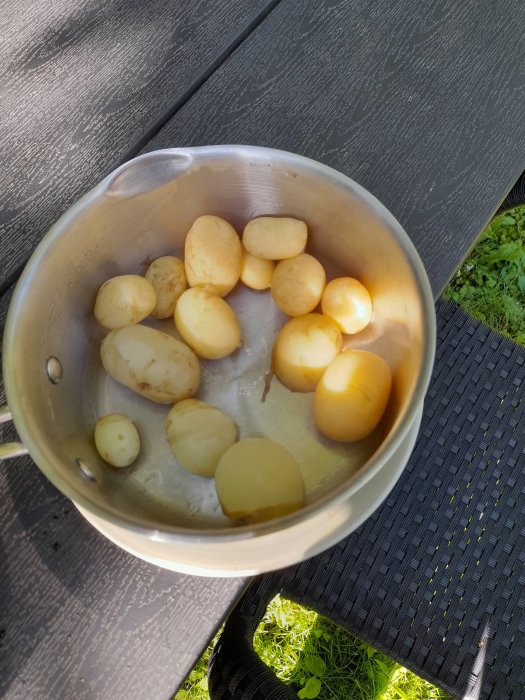 Nypotatis i durkslag på ett utomhusbord i solsken.
