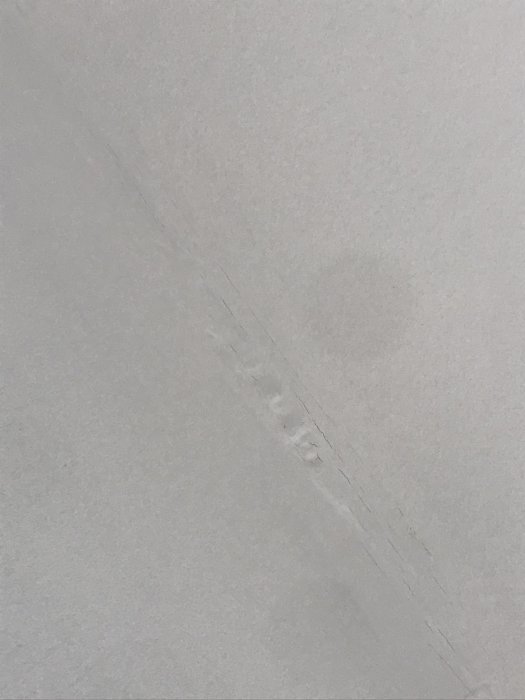 Ojämn och gropig fog på vit vägg som behöver slipas och målas om.