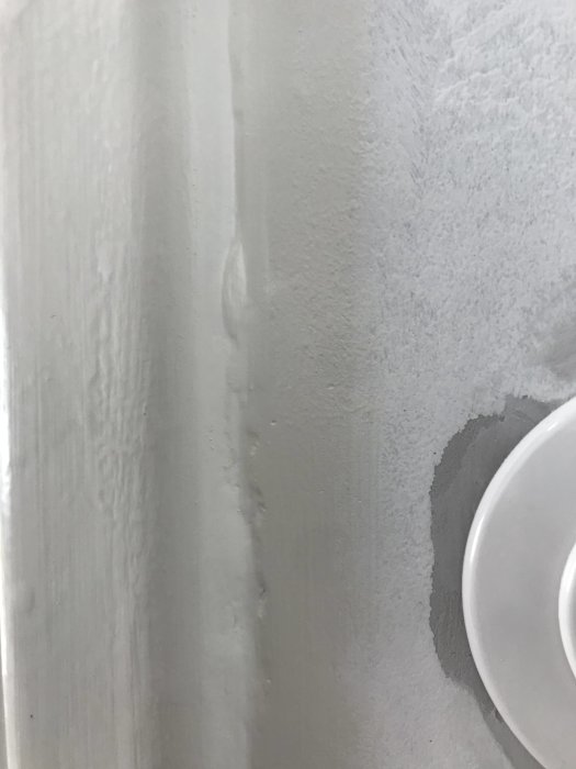 Ojämna och gropiga fogar på vitmålad vägg, synliga steg och dåligt utförd spackling.