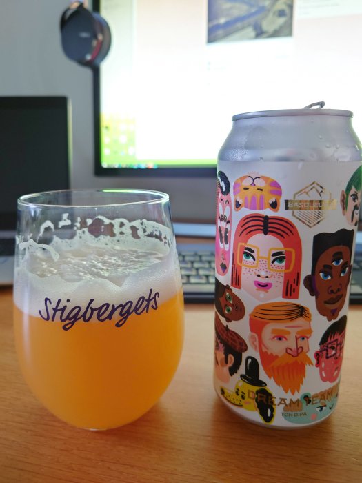 Ett glas öl märkt "Stigbergets" och en färggrann burk med folkligt motiv på ett skrivbord framför en datorskärm.