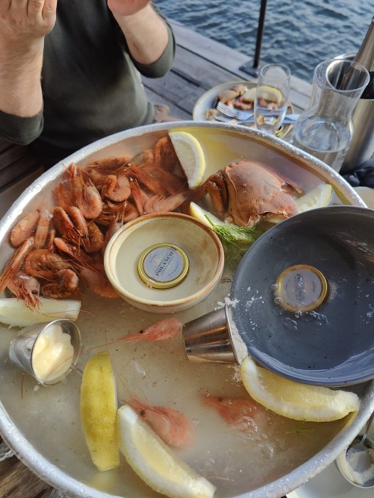 Rester av skaldjursmåltid med skaldjursrester, citron och såsskål på ett bord.