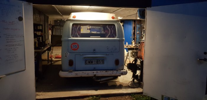 Vintagebuss parkerad i ett garage med verktyg och utrustning runtomkring.